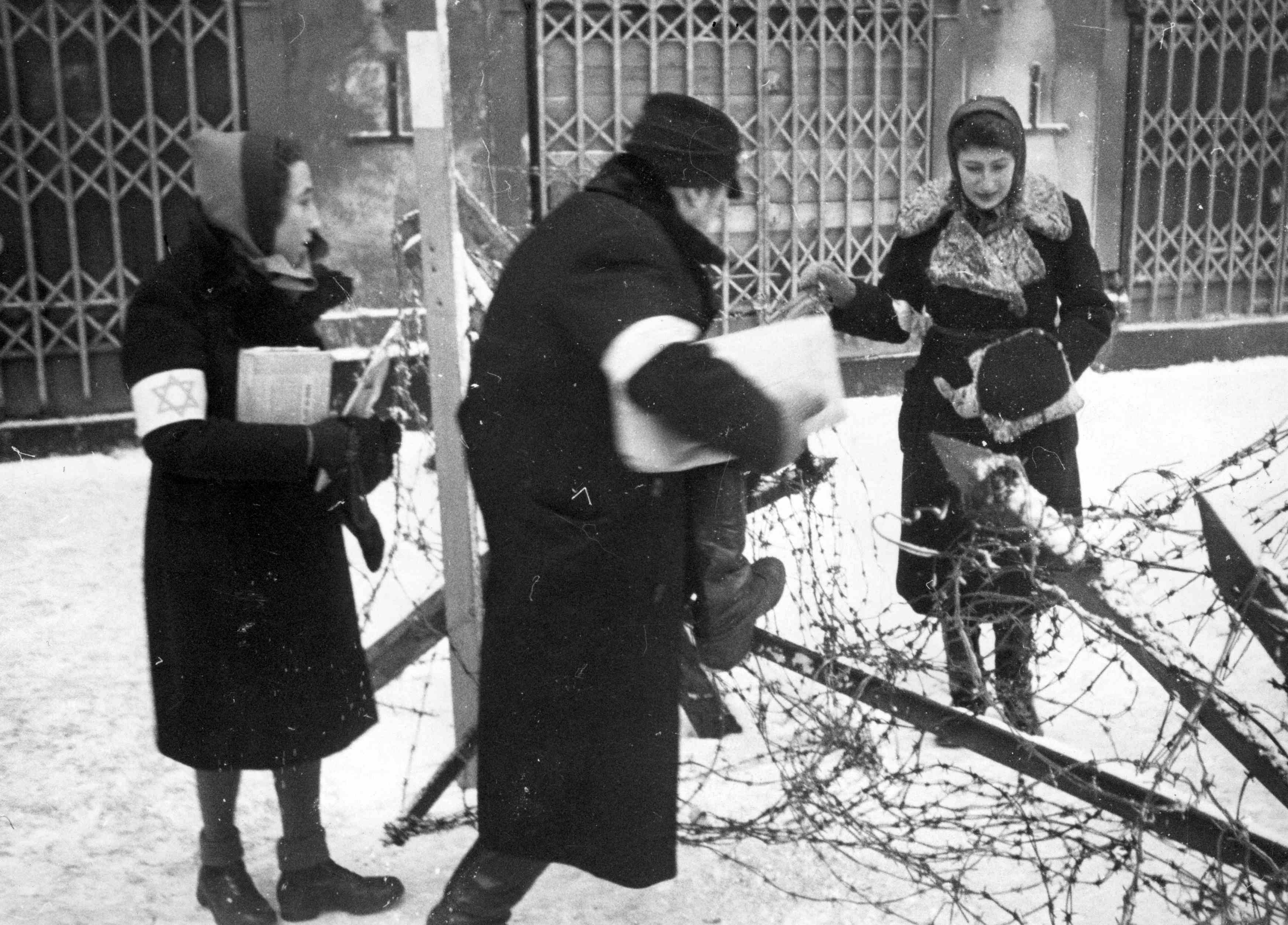 Warszawa. Dwoje Żydów przechodzi przez zasieki z drutów kolczastych w getcie. Fot. NAC