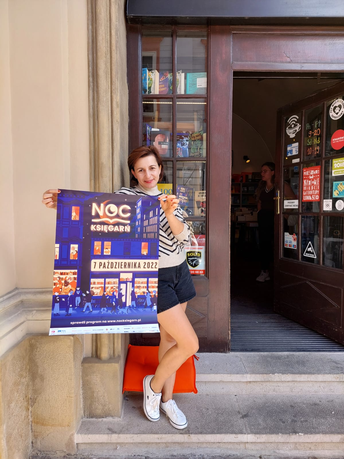 Milena Gumienny na stopniach Księgarni De Revolutionibus Books&Cafe zaprasza na Noc Księgarń