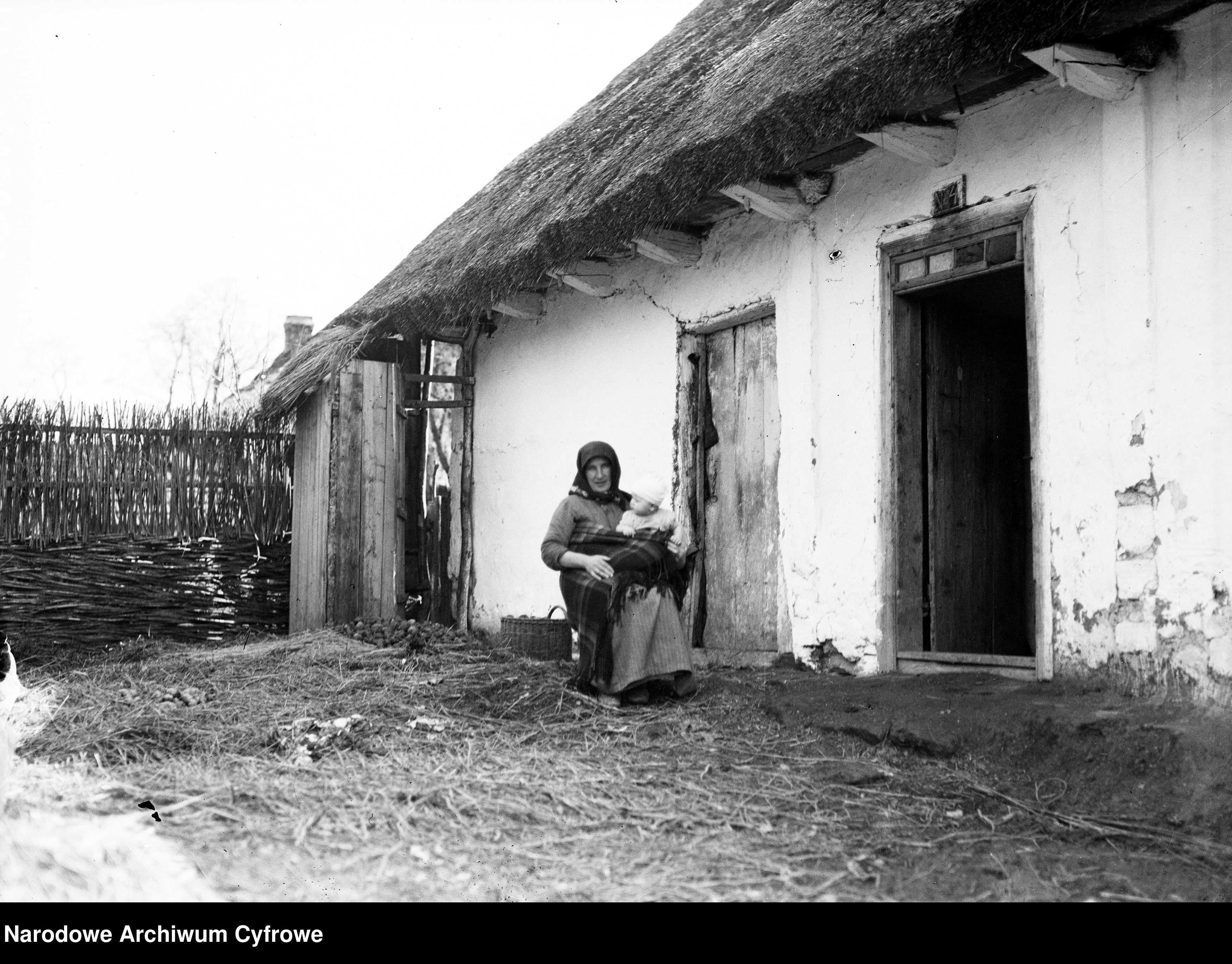 Kobieta z dzieckiem przed wiejską chatą/źródło: NAC